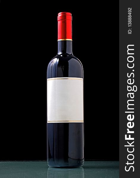 Bottle of red with a white textured label and red cap on black background with copy space for your text. Bottle of red with a white textured label and red cap on black background with copy space for your text