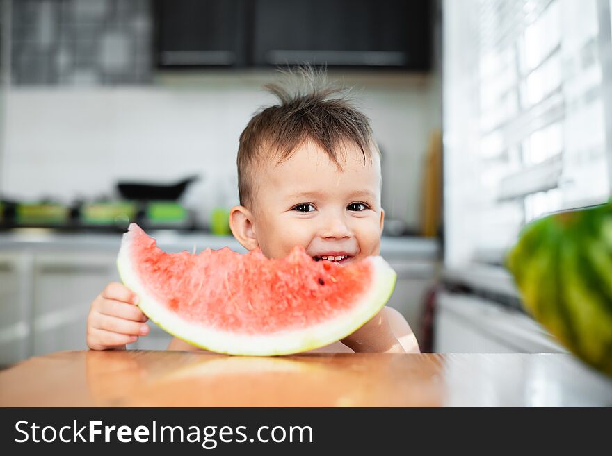 Cute little boy eating watermelon in the kitchen, very cute