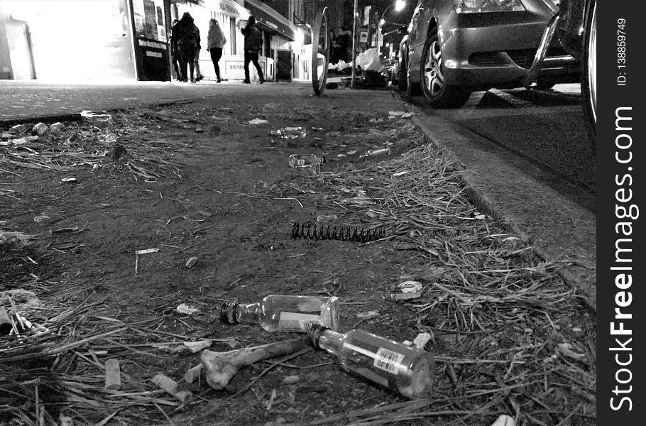 Young men and women enter nightclub in New York City through open door. Cars parallel parked next to barren dirt patch withy bones, empty mini vodka bottles, dead grass. Young men and women enter nightclub in New York City through open door. Cars parallel parked next to barren dirt patch withy bones, empty mini vodka bottles, dead grass.