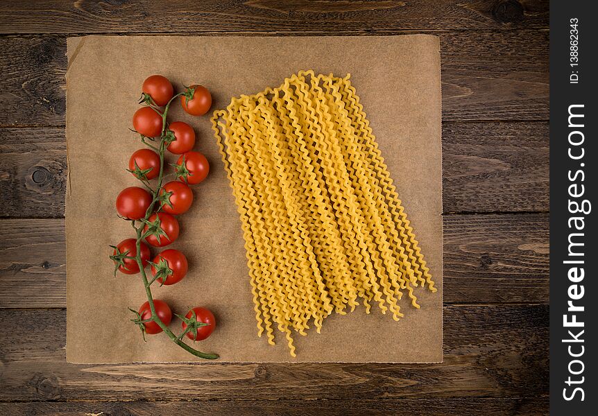 Pasta and tomatoes on dark wooden background with copy space. Top view. Vegetarian food, health or cooking concept