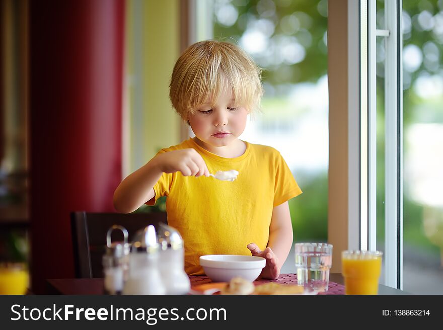 Little boy eating healthy breakfast in hotel restaurant. Tasty meal in home. Healthy food for kids