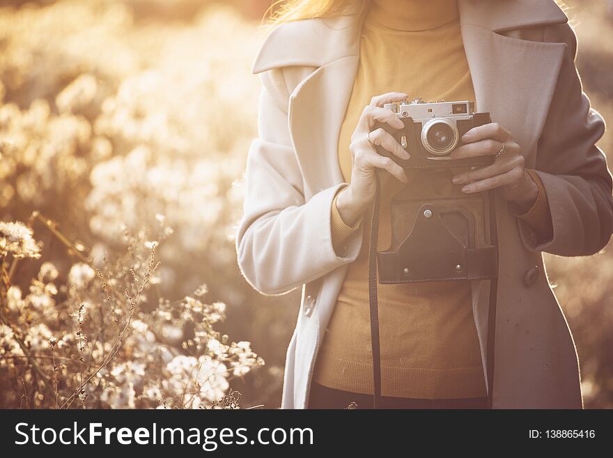 Vintage autumn. girl with a vintage camera walks in the fields of fluffy dandelions at sunset. Vintage autumn. girl with a vintage camera walks in the fields of fluffy dandelions at sunset