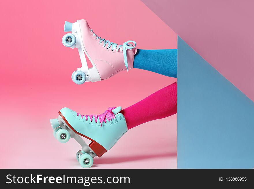 Woman with vintage roller skates on color background, closeup