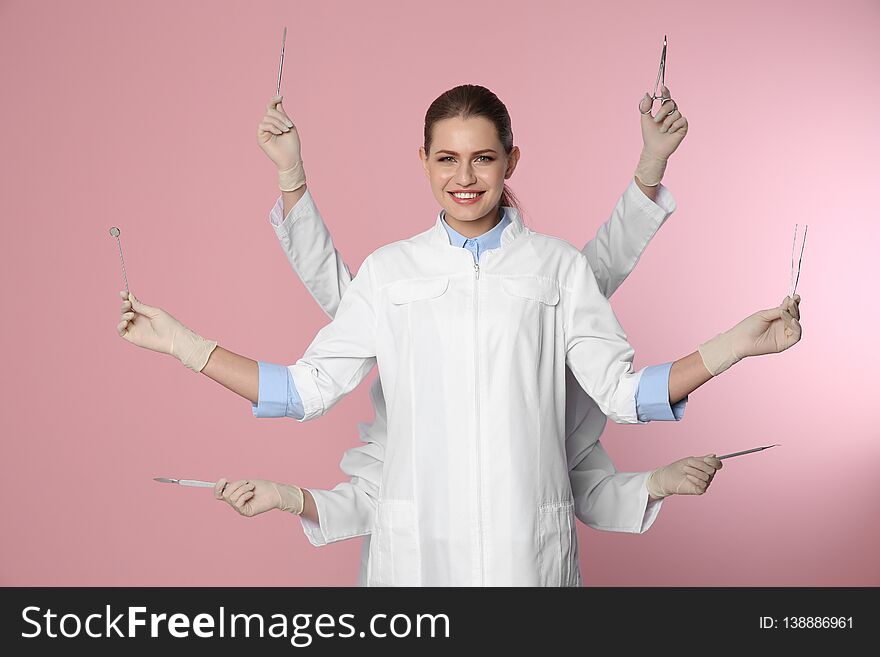 Female dentist with multiple hands holding tools on color background