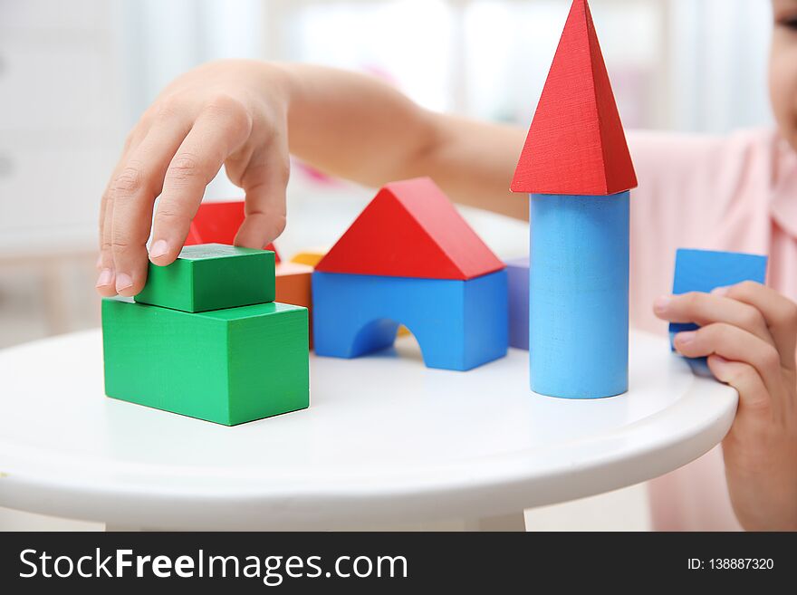 Cute child playing with colorful blocks at home