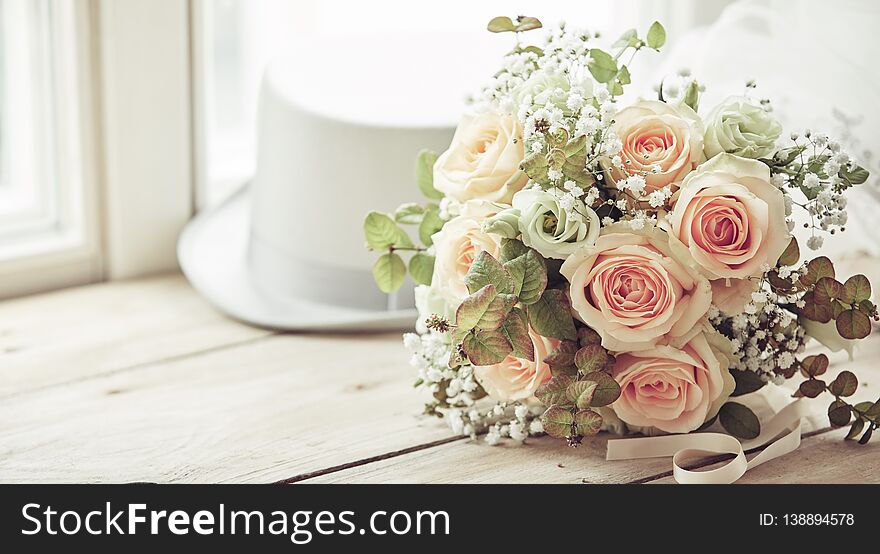 Broom white hat and bridal bouquet of pink roses in marriage day composition on wooden window sill with copy space