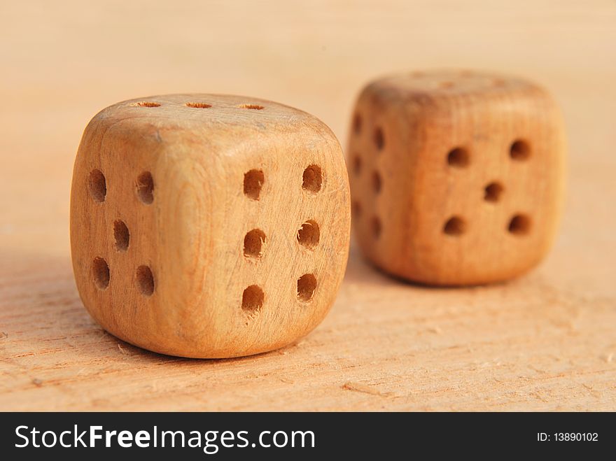 Two wooden cubes for dicing isolated on a piece of wood