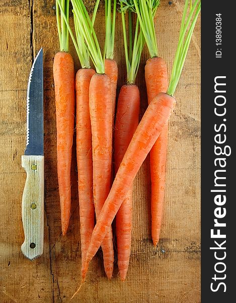 Carrots and knife on a rustic wooden surface. Carrots and knife on a rustic wooden surface.