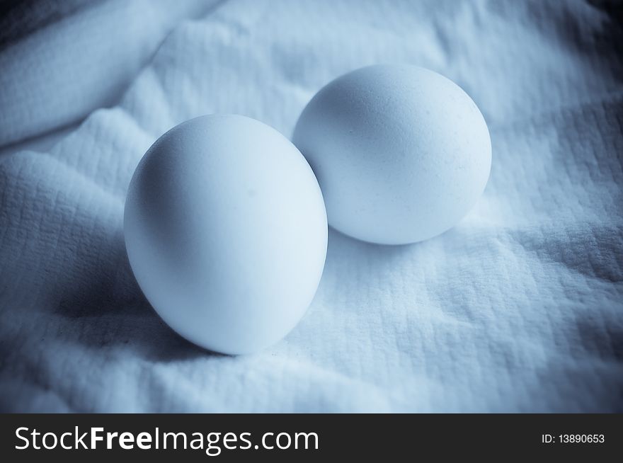 Three white eggs on light background close up