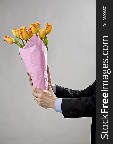 Man's two hands holding a bouquet of orange tulips. Man's two hands holding a bouquet of orange tulips