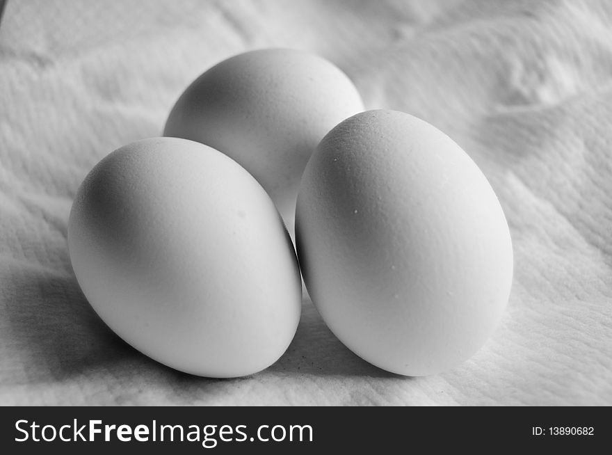 Three white eggs on light background close up