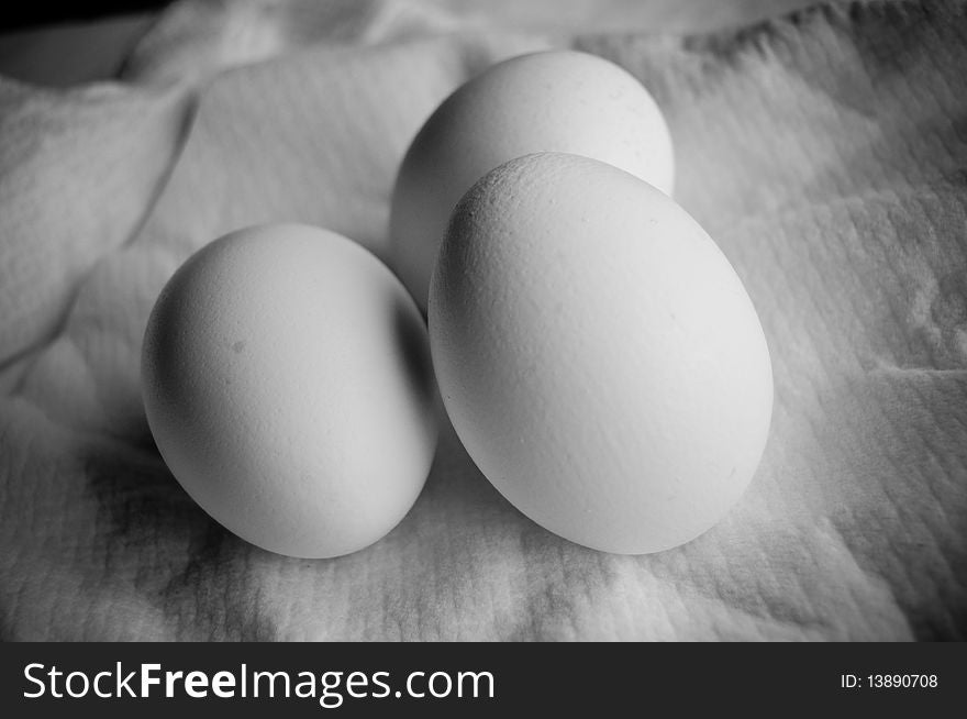 Three white eggs on light background close up