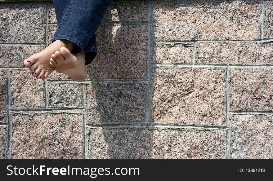 Barefoot woman sitting on a stone wall. Barefoot woman sitting on a stone wall
