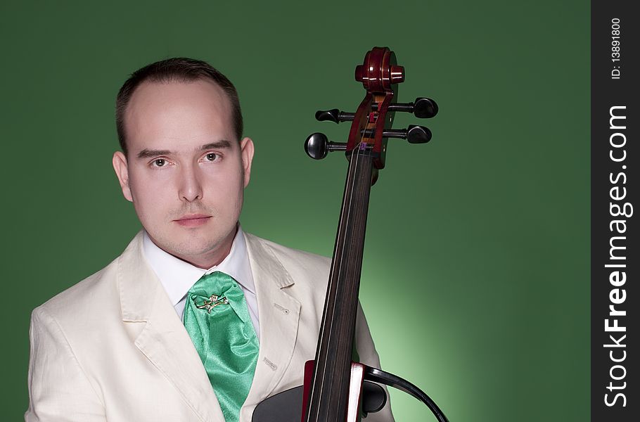 Portrait of young man with electic cello on green background. Portrait of young man with electic cello on green background