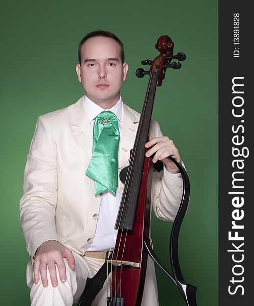 Portrait of young man with electic cello on green background. Portrait of young man with electic cello on green background