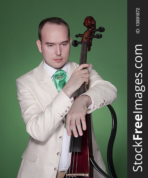 Portrait of young man with electic cello on green background. Portrait of young man with electic cello on green background