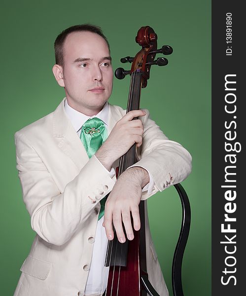 Portrait of young man with electic cello on green background. Portrait of young man with electic cello on green background