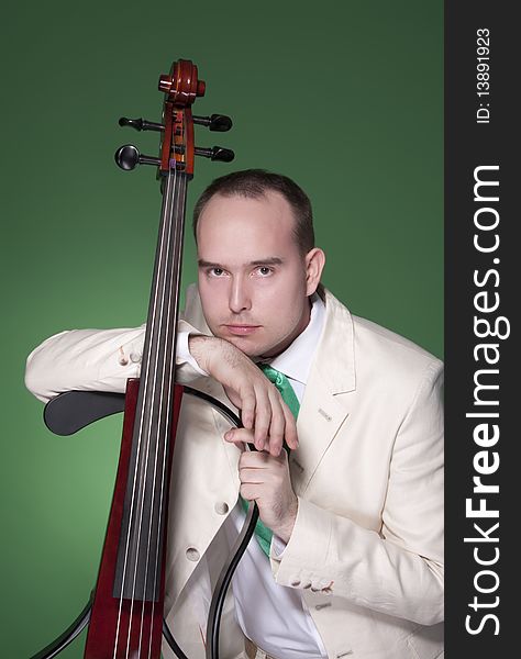 Portrait of young man with electic cello on green background. Portrait of young man with electic cello on green background