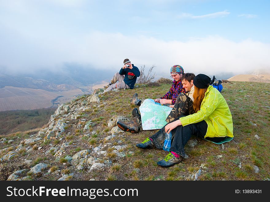 Hikers sit on the peak and exploring the map