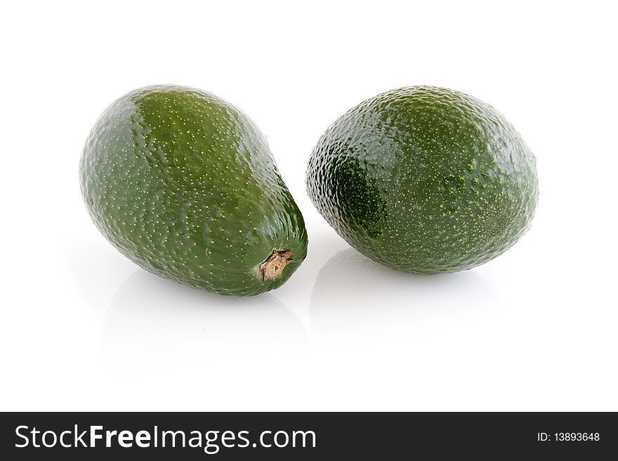 Two avocado fruits, isolated on white, reflective background. Two avocado fruits, isolated on white, reflective background.