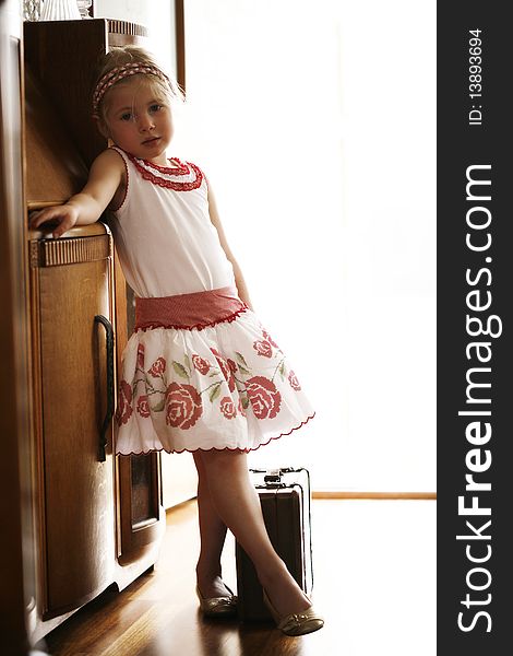 Little blonde girl waiting at front door ready to go on trip with suitcase in hand. Little blonde girl waiting at front door ready to go on trip with suitcase in hand.