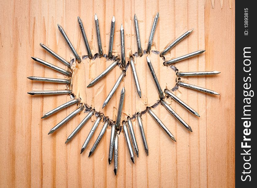 A heart from nails  on wooden desk. A heart from nails  on wooden desk