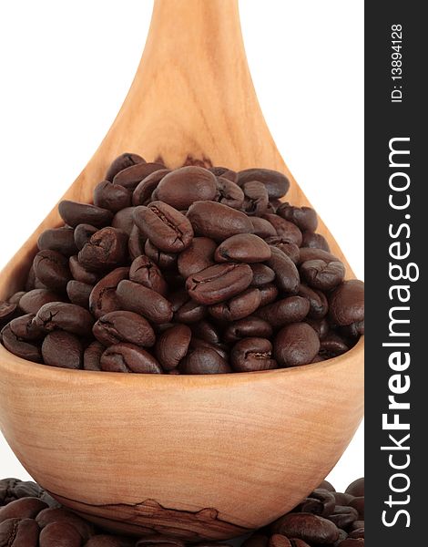 Coffee beans in an olive wood spoon, over white background.