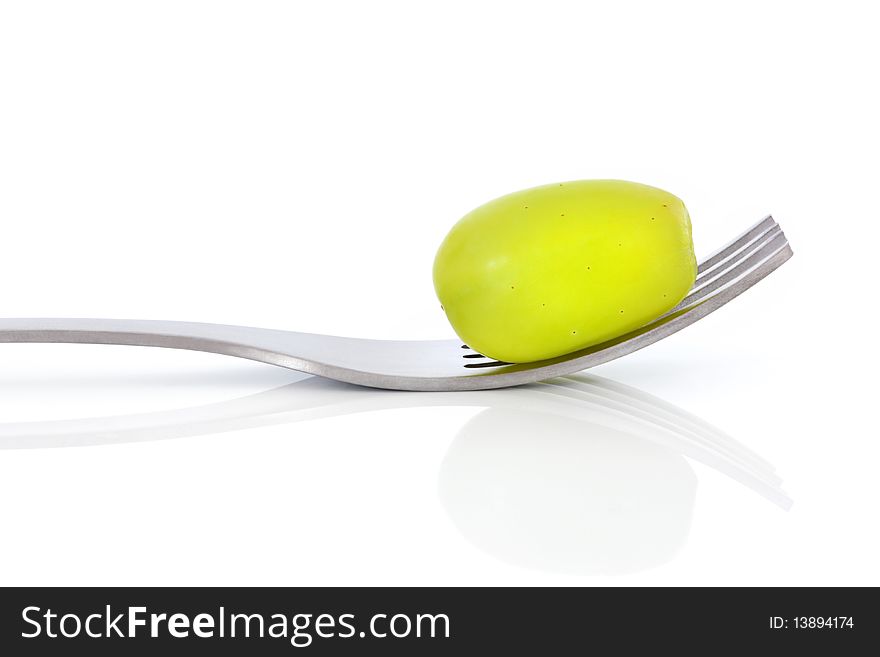 Green grape on a stainless steel metal fork, isolated over white background with reflection. Green grape on a stainless steel metal fork, isolated over white background with reflection.