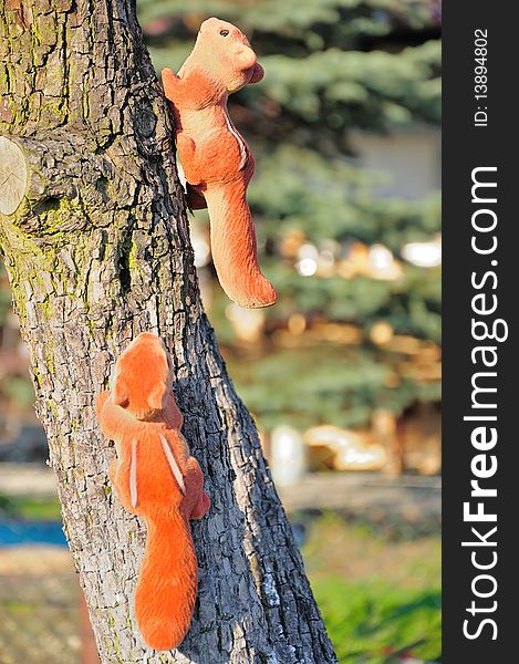 Picture shows a garden decorations. Two artificial squirrel clinging to a tree