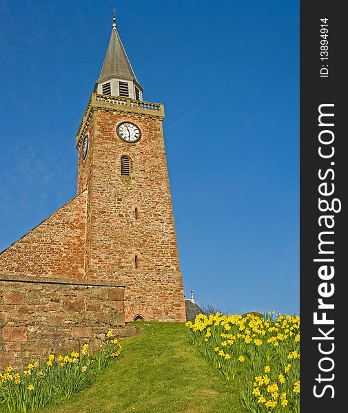 An image of a path up the hill to a church with a border of daffodils. An image of a path up the hill to a church with a border of daffodils.