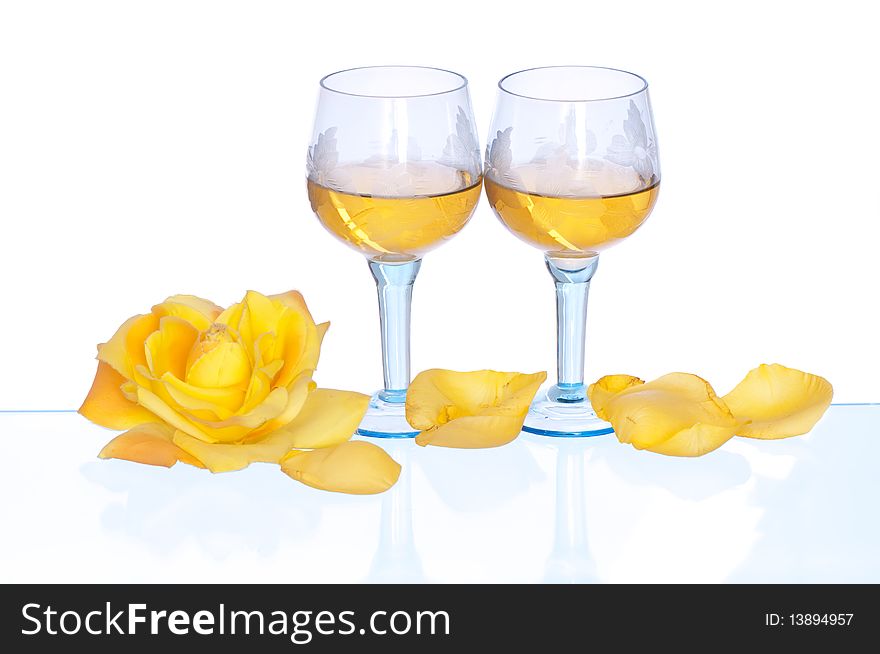 Two tumblers with white wine and yellow rose on the party. Two tumblers with white wine and yellow rose on the party