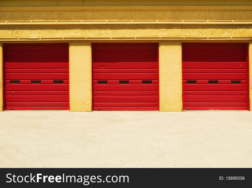 Three bright red identical doors in a yellow building, with space for text. Three bright red identical doors in a yellow building, with space for text.