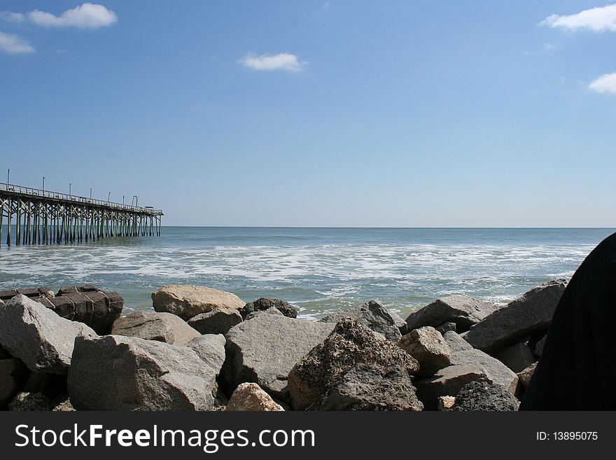 Beach scene with boulders and a pier. Beach scene with boulders and a pier