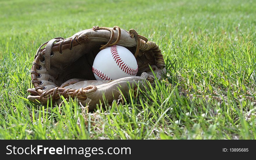 Baseball glove and ball on grass field. Baseball glove and ball on grass field.