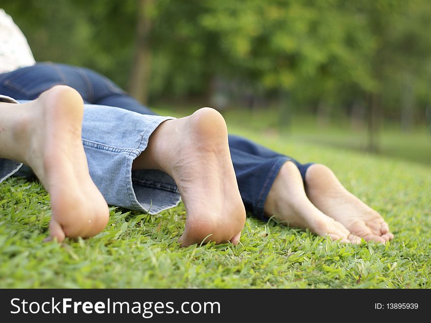 Couple's feet at park, relaxing on green grass outdoors