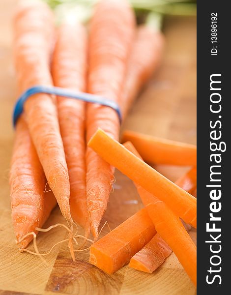 Carrots with green tops in bunch accompanied by carrot sticks