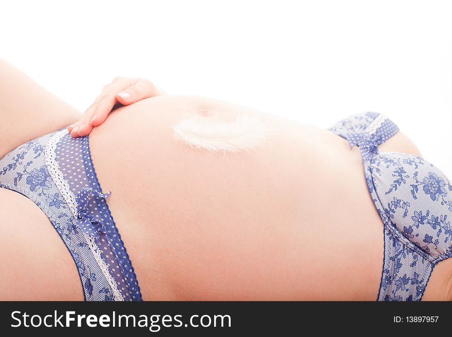 Bird feather lying on pregnant belly on white