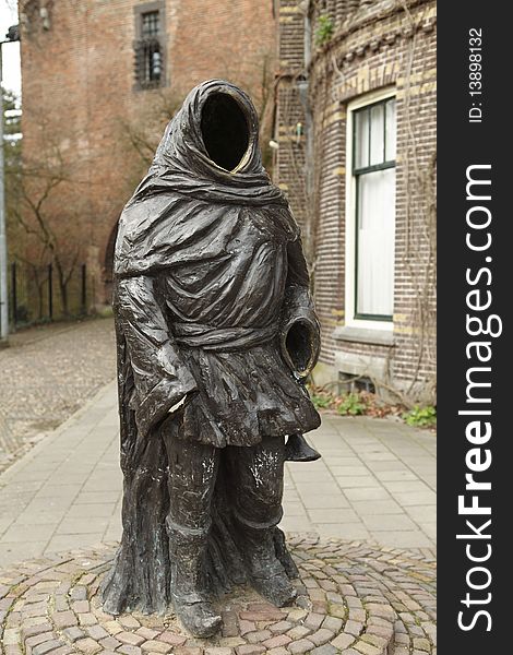Statue of a faceless man holding a trumpet