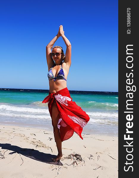 Young beautiful girl in a red scarf exercise on the beach