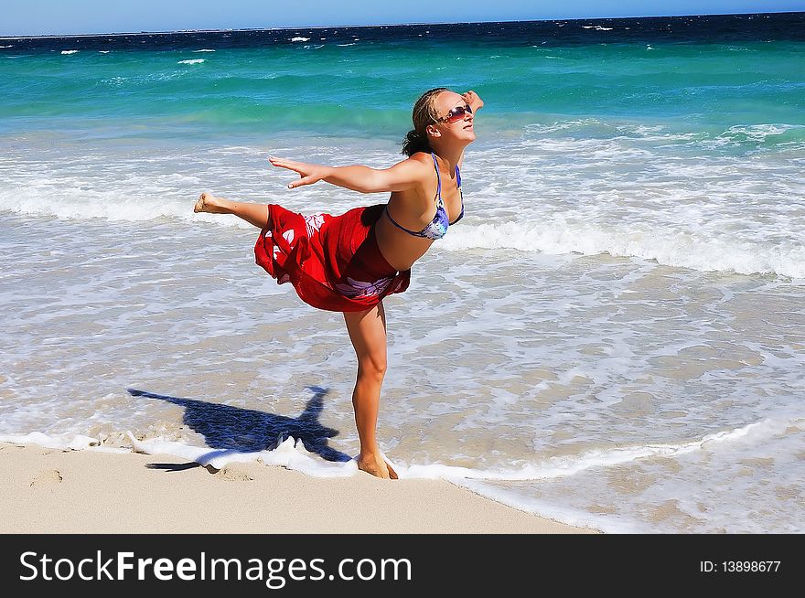 Young beautiful girl in a red scarf exercise on the beach