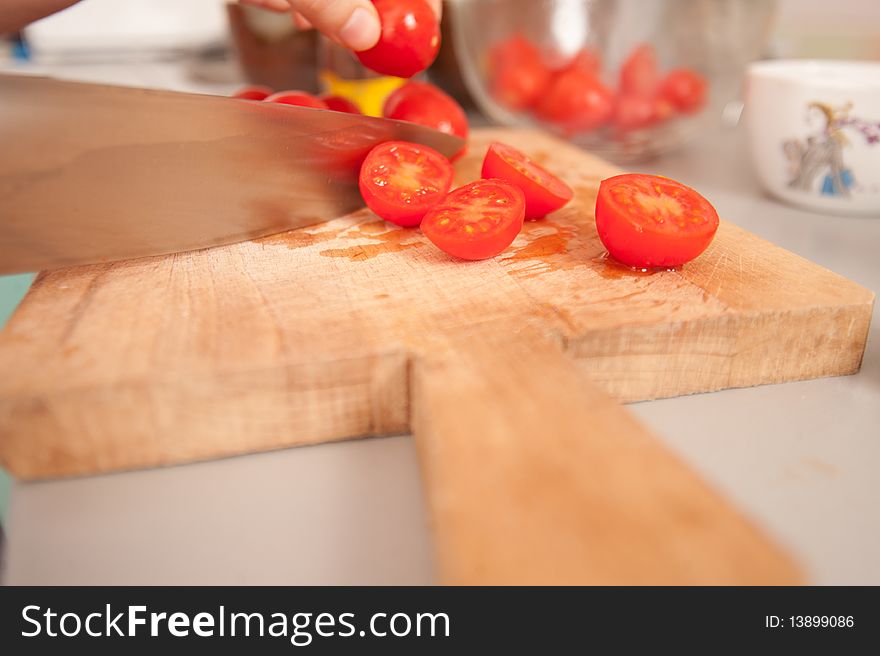 Cutting cherry tomatoes on a wooden cutting board