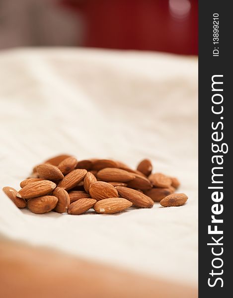 Whole almonds on a white table cloth with blurred foreground and background.