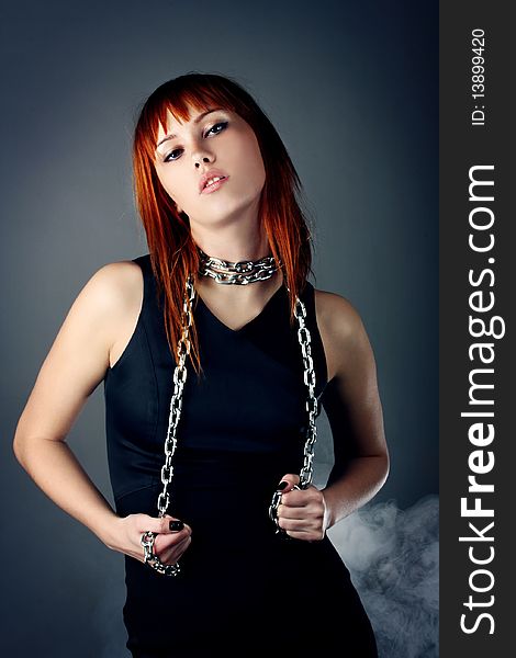 Beautiful sexy woman with red hair. girl twisted with a metal chain