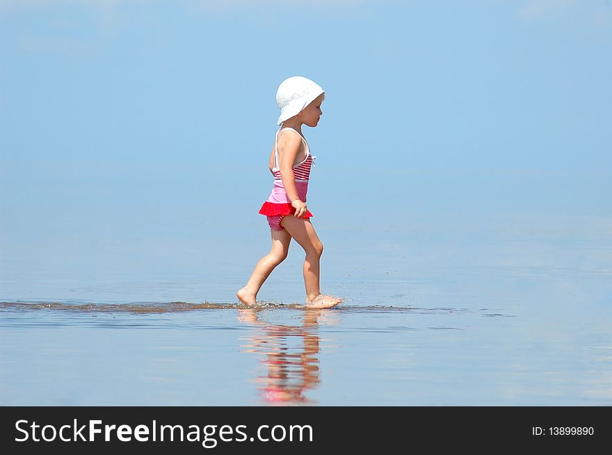 The little girl in a bathing suit goes on water. The little girl in a bathing suit goes on water