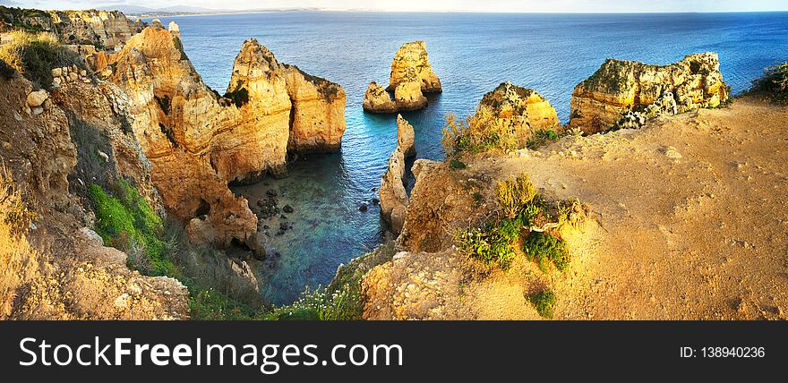 Amazing panoramic view of Ponte de Piedade in Algarve, Portugal, red and yellow majestic cliffs rising over the waters of the Atlantic ocean, fascinating seascape near the town of Lagos