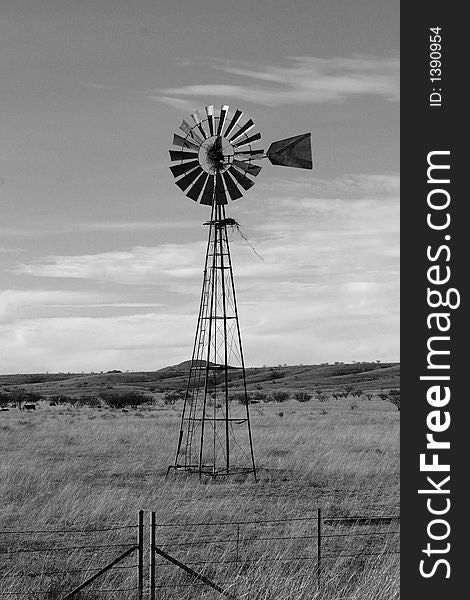 A black and white photo of a windmill in the country. A black and white photo of a windmill in the country.