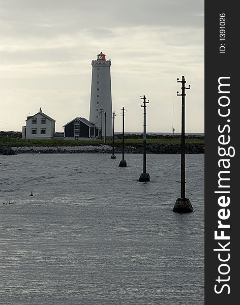 Lighthouse with power transmitting poles leading into in Reykjavik in Iceland.