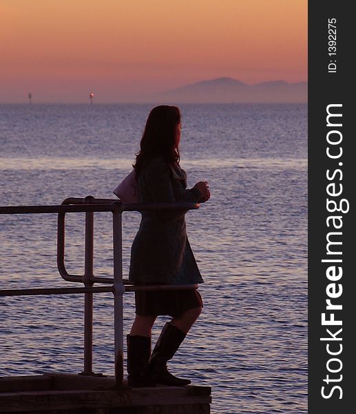 Girl on a pier looking out towards the sea