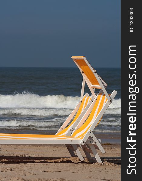 Two beach chairs in the sand with the sea/ocean on the background, plenty of copyspace. Two beach chairs in the sand with the sea/ocean on the background, plenty of copyspace