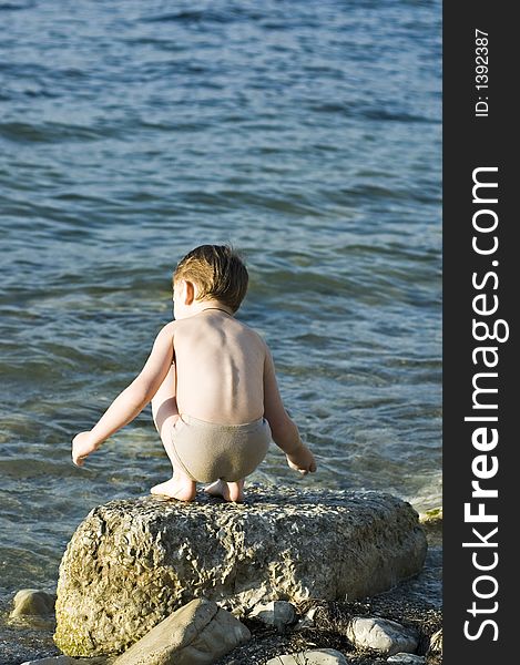 The child plays on a stone beach. The child plays on a stone beach